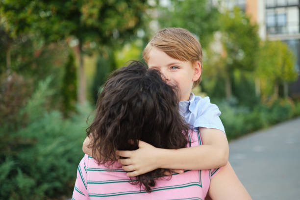 istock small cute son hugging mother looking at camera outdoor on summer background 2151250979