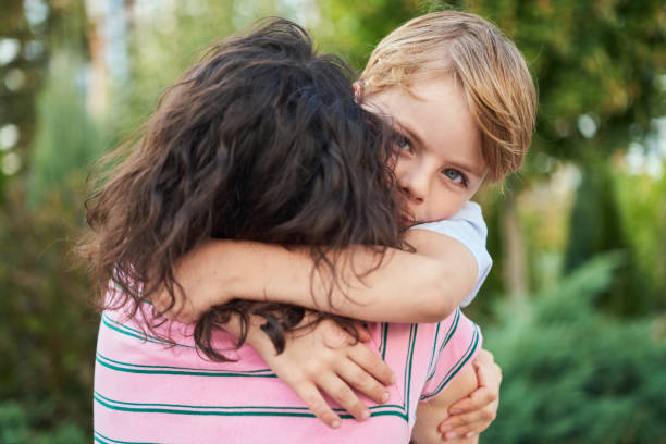 istock small cute son hugging mother looking at camera outdoor on summer background 2151251428
