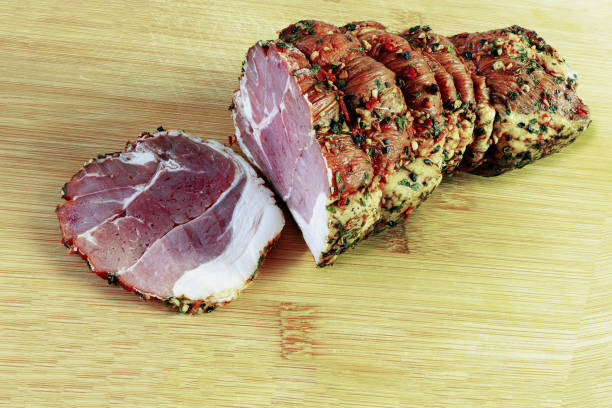 Smoked spiced pork roll with one slice on a bamboo cutting board close-up