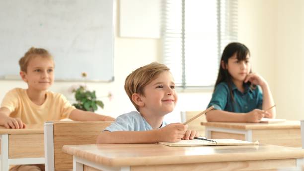 istock Smart caucasian boy raising hand for asking teacher at classroom. Pedagogy. 2151256542