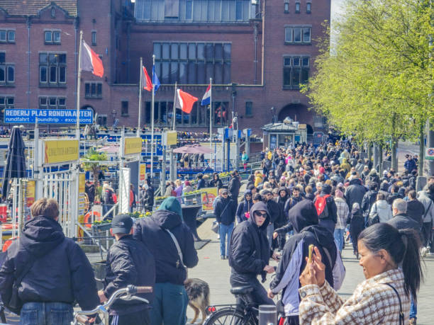 Amsterdam Netherlands 21 April 2024, A vibrant scene unfolds as a large group of people, hailing from diverse backgrounds, traverse through a lively urban street