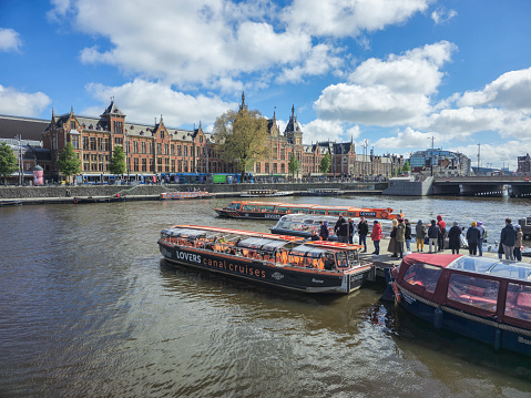 Amsterdam Netherlands 21 April 2024 A group of boats peacefully float on top of a tranquil river, reflecting the clear blue sky above.