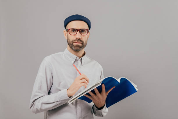 istock Scholarly man in glasses pondering over a notebook, embodying introspection. 2151259142