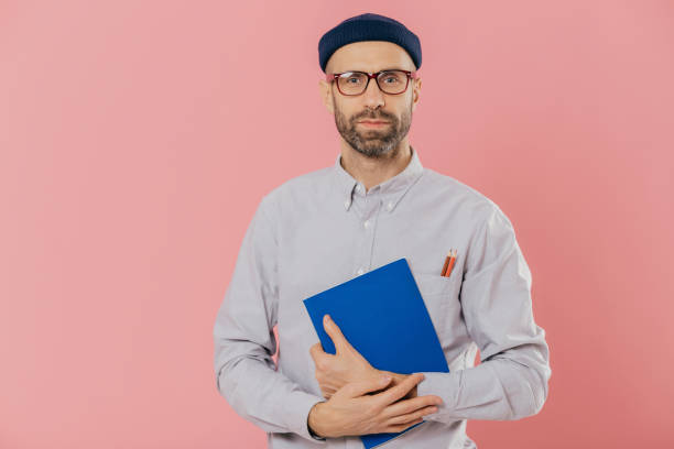 istock Scholarly man in glasses clutching a folder on pink background. 2151259164