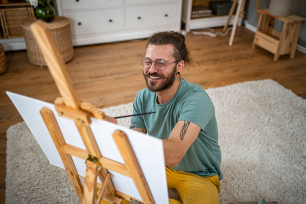 istock Modern man artist paints on canvas at home, enjoys his hobby 2151260201
