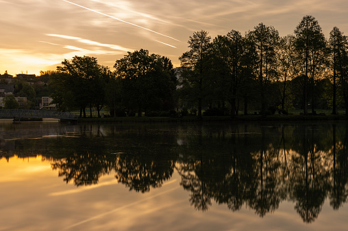 Long exposure shot of the Boating Lake with houses in the background in Ajka at sunrise on springtime.