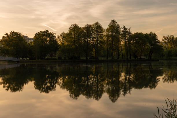 Long exposure shot of the Boating Lake with buildings in the background in Ajka at sunrise on springtime.
