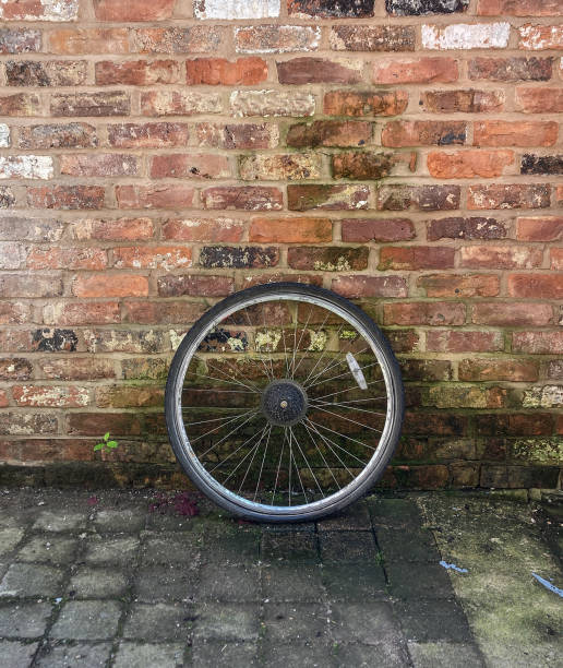 istock Spare wheel leaning against an old weathered brick wall, looking alone stolen or dumped. 2151265262