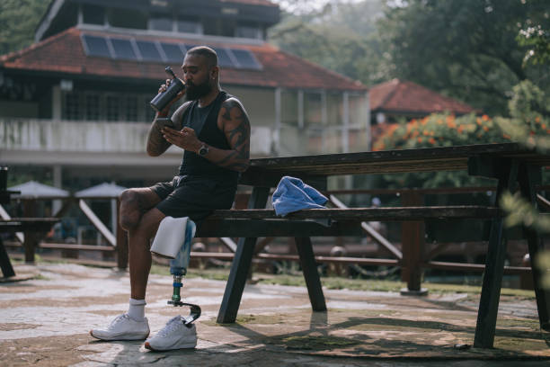 istock Indian Athlete with disabilities resting sitting on park bench using smart phone reading workout performance after morning exercise 2151265341