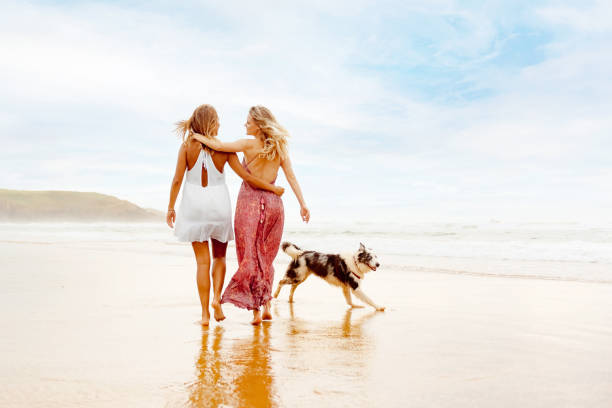 istock girls walking on the beach with their dog 2151265705
