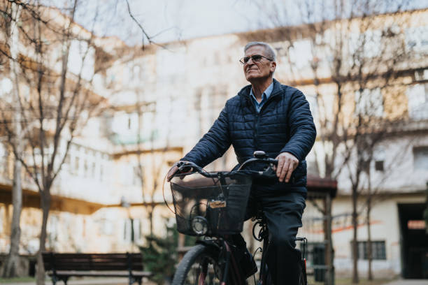 A mature, active senior gentleman cycling confidently on his bike through a tranquil urban park, embracing an active lifestyle.