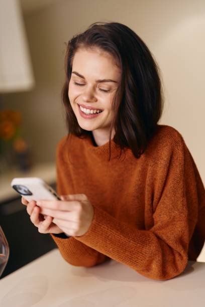 istock Happy Young Woman Holding Smartphone, Smiling, and Using Online Communication App on Sofa in Home 2151266766