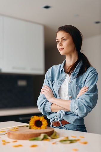 Calm and Confident: Young Caucasian Woman, an Attractive Portrait in a Modern, Stylish Kitchen, Standing by the Light-Filled Window, Posing near the Table with Healthy Diet Breakfast, showcasing Her Natural Beauty and Charming, Lovely Smile.