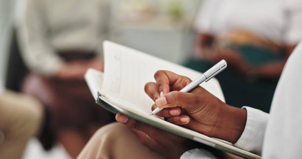 istock Therapist, hands and writing in therapy or closeup for group consultation, support and helping for mental health. Psychologist, pen and book for review, feedback and patient information in counseling 2151270254
