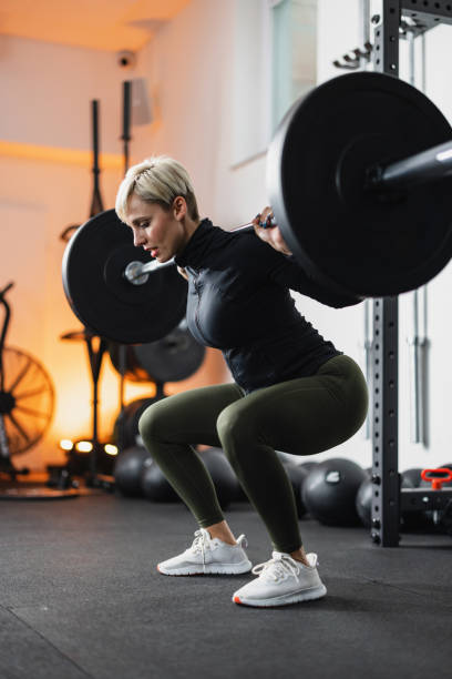 istock Focused Female Athlete Performing Barbell Squats 2151270482