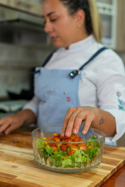 The beautiful Latina chef, 20 to 29 years old, prepares a cheese board from her kitchen at home wearing her kitchen uniform