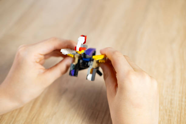 istock boy created and manipulates with transformer robot, child plays with colored plastic parts constructor, creates equipment, development of creativity, fine motor skills 2151273741