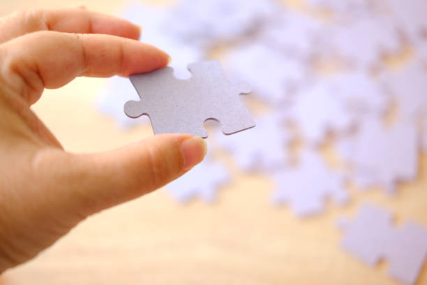 istock female hand holds cardboard puzzle piece, logical skills, puzzle solving and memory improvement, business concept for completing 2151274273