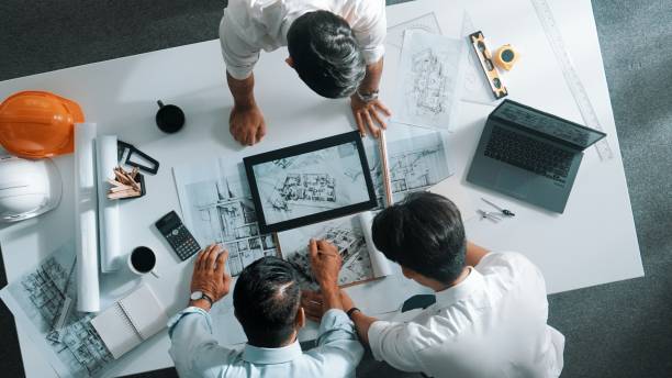 istock Top view of manager looking at plan while designer hold blueprint. Alimentation. 2151275017