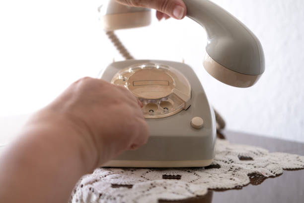 mature female hand removing Handset, rotating Dialer on Old white Rotary Telephone with Disc Dial with finger, putting retro phone reciver down, hanging up, calls helpline, psychological support