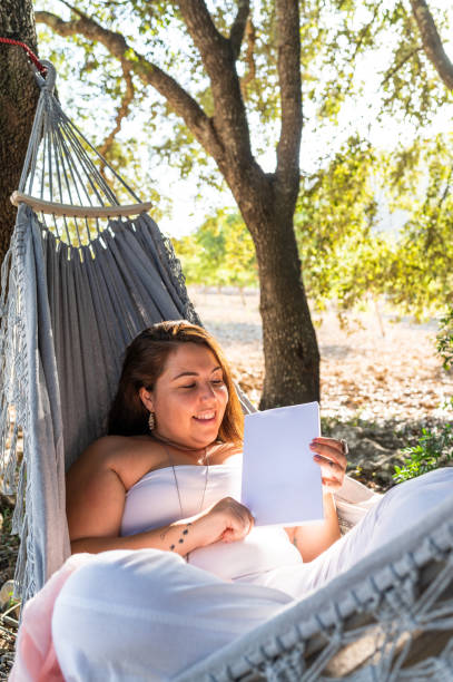 istock Woman reading lying on hammock in the forest 2151277992