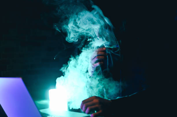 istock Hacker smokes vape in a dark room. 2151278041