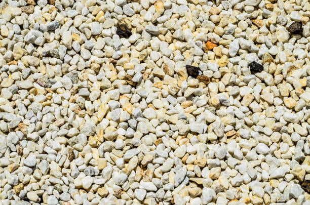 A white gravel with black specks on it. The gravel is spread out and has a rough texture