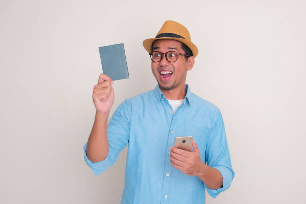 istock Adult Asian man looking to passport document that he hold with excited expression 2151280619