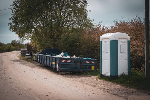 istock Next to a road is a large blue container for construction waste and a construction site toilet 2151282762