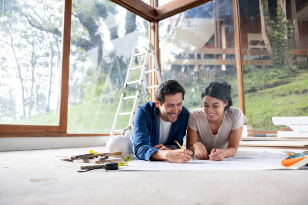 istock Couple renovating their house and smiling while looking at a blueprint 2151288691