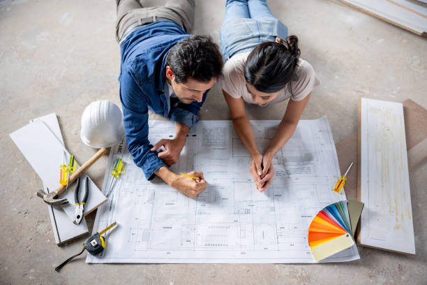 istock Couple renovating their house and sharing ideas while looking at a blueprint 2151288700