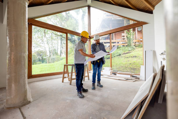 Architect and construction worker looking at a blueprint while renovating a house
