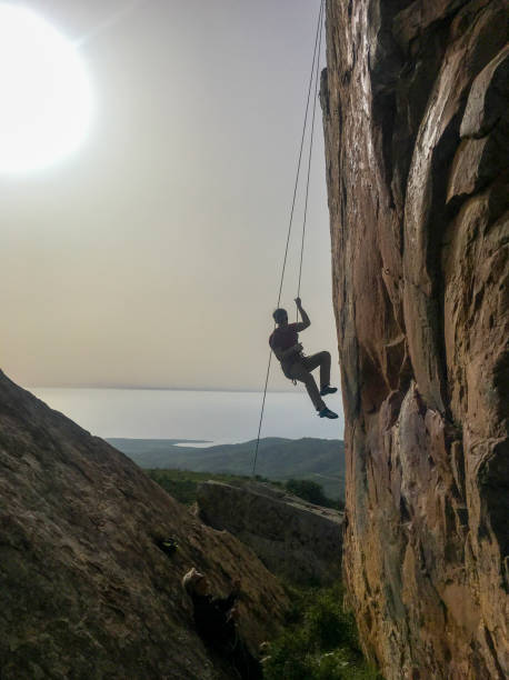 istock Young man climbs cliff face with rope 2151294669
