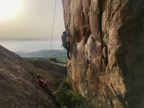 istock Mature man climbs cliff face with rope 2151294775
