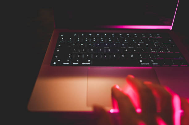 istock hand typing on laptop computer keyboard and surfing the internet at night. 2151295102