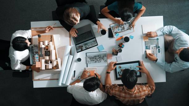 istock Top down view of architect team discussing and pointing blueprint. Alimentation. 2151295552