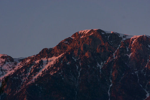 Snow capped mountain peaks illuminated in red sunlight at sunset