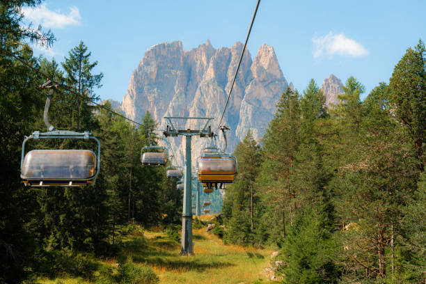 Chair lift in Dolomites in summer surrounded by pine trees