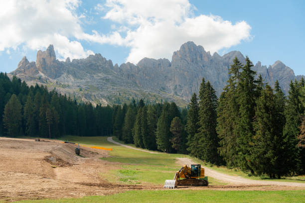 Excavator  working at ski resort in Dolomites in summer  getting ready for the season