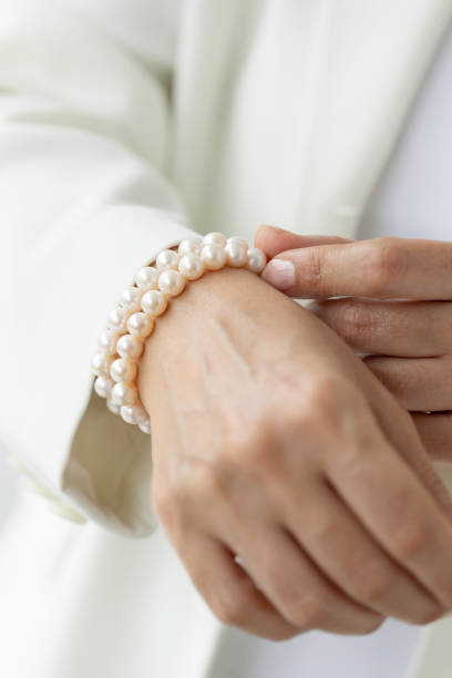Hand of unrecognizable female is holding white pearl necklaces