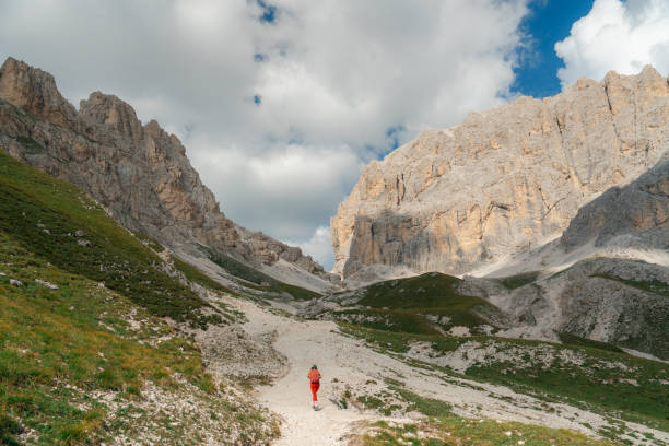 Cheerful woman with backpack wearing cap  hiking in Dolomites
