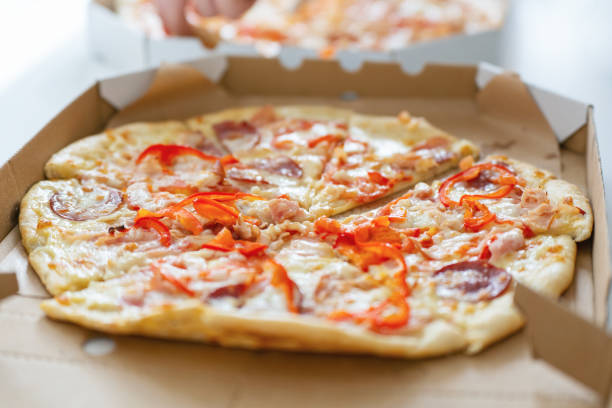 istock Hot fresh pizza cut into slices in a cardboard package on the table 2151312272