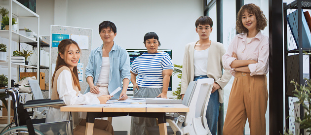 Group portrait of young adult Asian business people diverse team arms crossed, smiling. Stand together in corporate office. Generation Z millennial businesspeople, sustainable workplace lifestyle