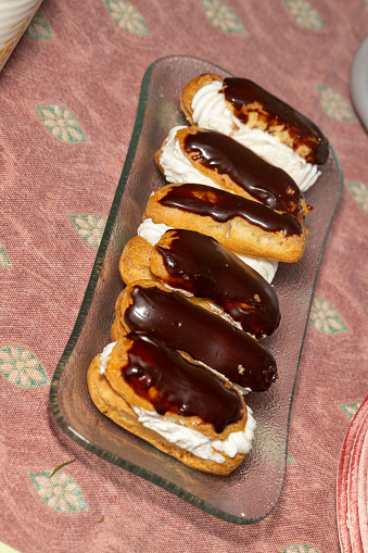 Delicious six eclairs filled with fresh cream and topped with chocolate icing
