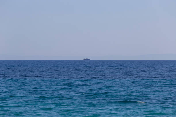 Fishing boat on distant blue sea horizon. Clear sky can be used as copy space.