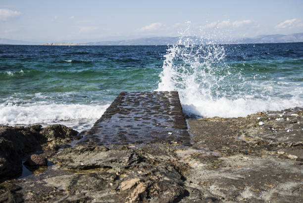 Mediterranean landscape - sea wave hitting a stone pier. Greece, island Aegina