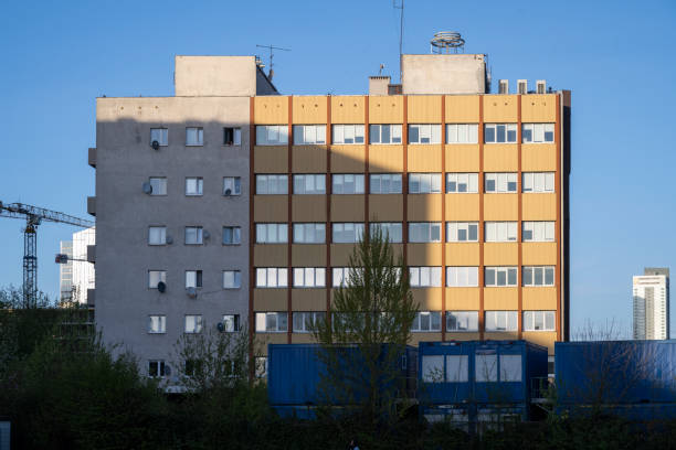 A medium-rise apartment building illuminated by the warm golden light of the setting sun, highlighting its geometric patterns and textures.