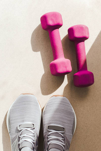 istock flat lay on a light background: gray sneakers, pink dumbbells 2151321864