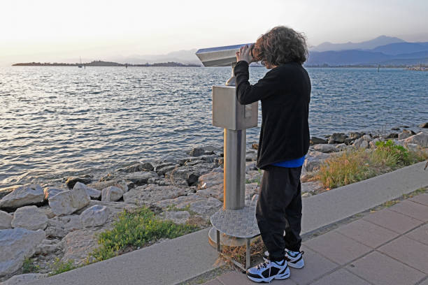 A boy looks at the sea panorama through binoculars.