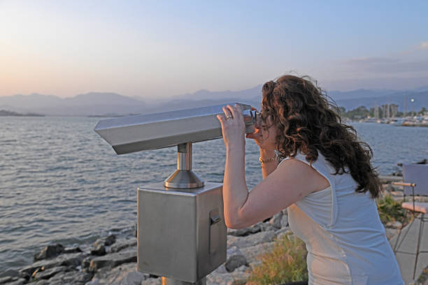 The woman is looking at the sea panorama through binoculars.